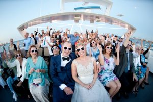 Fisheye of almost 100 wedding guests all wearing white sun glasses on the Chicago private yacht charter Anita Dee.