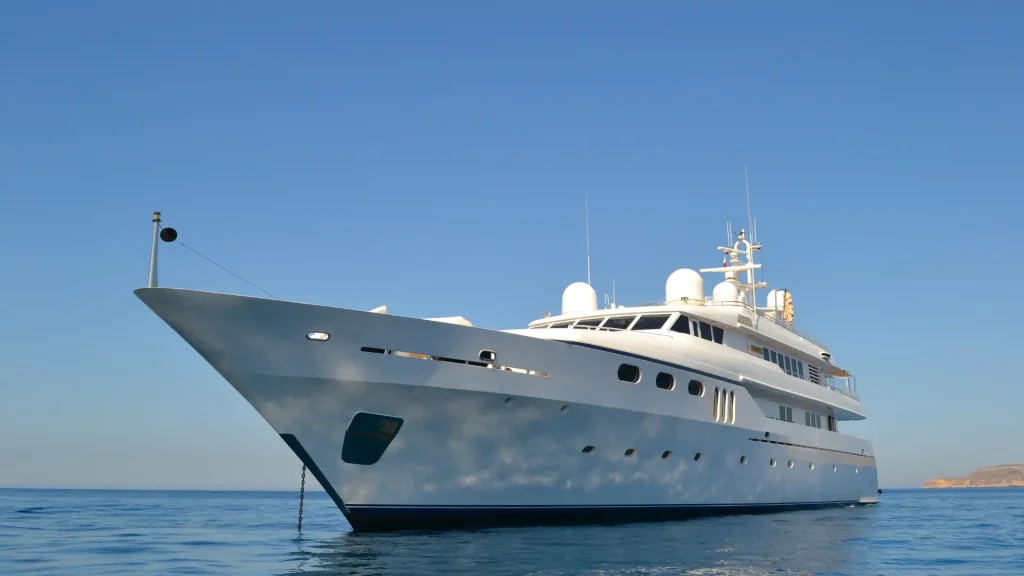 A large white luxury yacht floating on calm waters under a clear blue sky.
