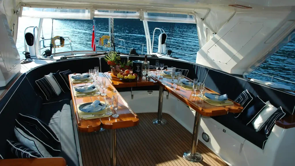 Dining area set up on a boat with a water view in the background.